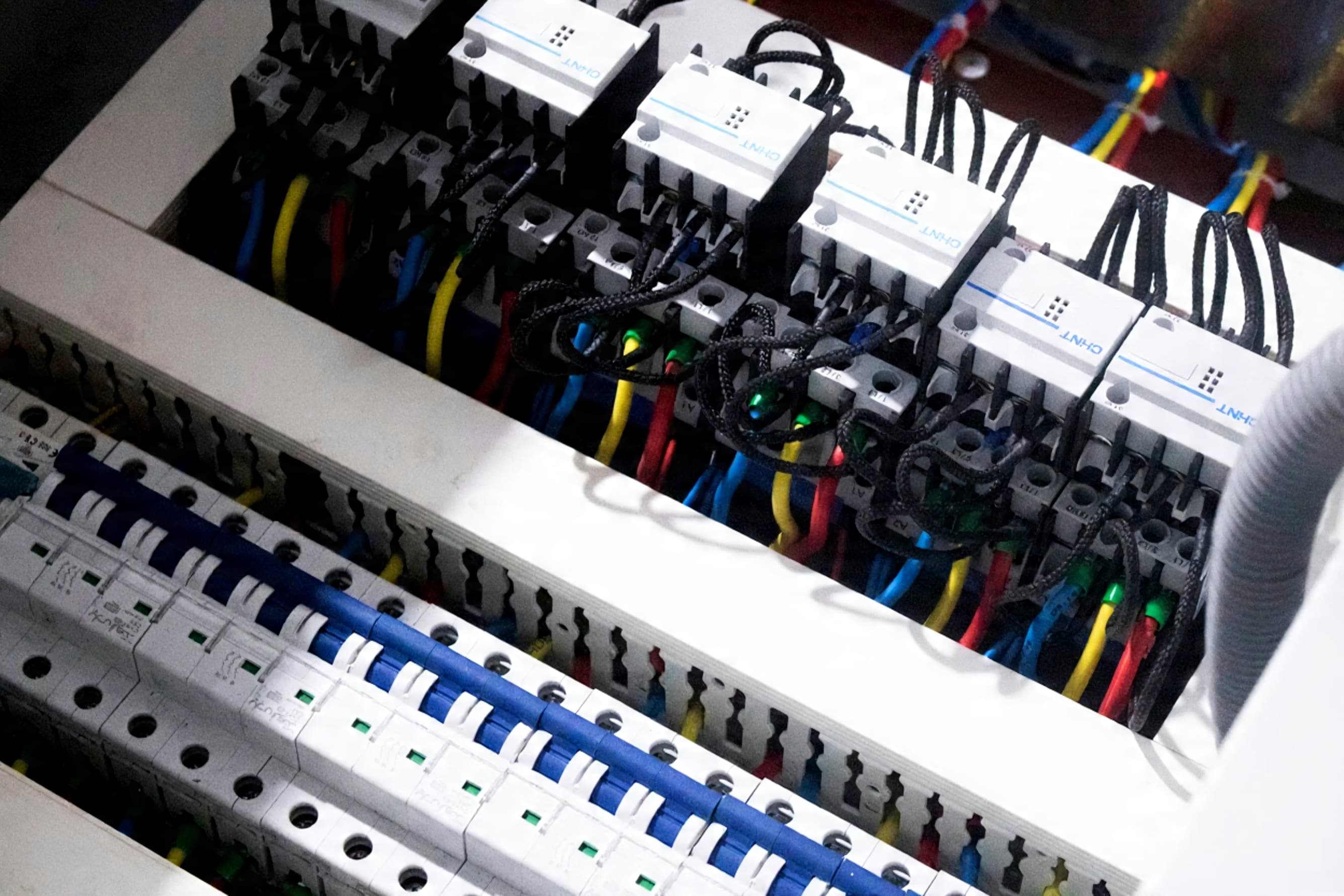 Nærbilde av sikringsskap med automatsikringer og fargekodede ledninger, som viser elektrisk installasjon ved bytte av sikringsskap.